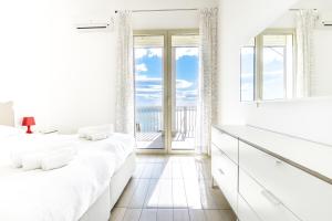 Habitación blanca con camas blancas y balcón. en Aurora Residence, en Gela