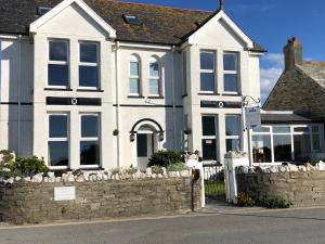 a house with a stone fence in front of it at Bosayne Guest House in Tintagel