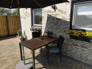 einen Holztisch und Stühle unter einem Sonnenschirm auf einer Terrasse in der Unterkunft De Kuiperij in Arcen
