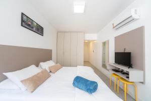 a white bedroom with a large bed and a tv at Apartamento impecável Fernando Machado 828 in Porto Alegre