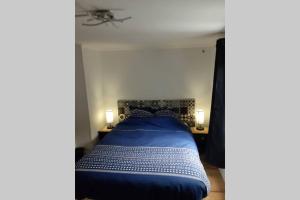 a blue bed in a room with two lamps at La Petite Maison Dans la Vallée in Avallon