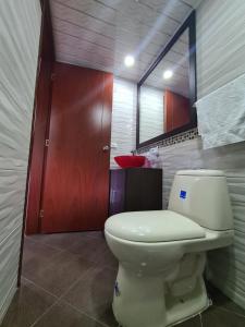 uma casa de banho com um WC e um espelho. em Hotel Casa Huesped Kiwi em Bogotá