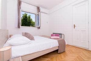 a bedroom with a white bed and a window at Apartmani Mlačić in Okrug Donji