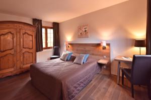 a bedroom with a large bed and a desk and a desk at Hôtel de l'Ange in Niedermorschwihr