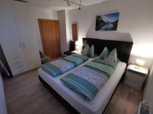 a bedroom with a large bed with blue and green pillows at Ferienwohnung Magdalena in Stumm