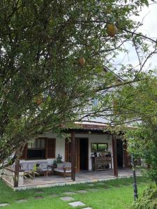 a house with a porch with a table and benches at Pousada Romã in Paraty