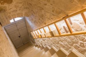 Una escalera en una habitación con paredes de piedra y ventana en La Casa di Agata, en Ceglie Messapica