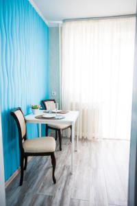 チュメニにあるApartment on Maksima Gorkogo 10の青い壁の客室で、テーブルと椅子が備わります。