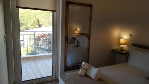 a bedroom with a bed and a mirror and a balcony at Alkyon Suites in Áyios Vasílios +25 photos