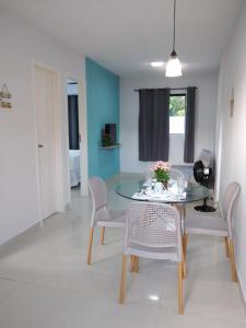 a dining room with a glass table and chairs at Marville Flats in Maragogi