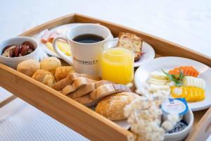 a tray of breakfast foods and a cup of orange juice at Intercity Portofino Florianópolis in Florianópolis