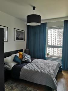 a bedroom with a large bed with blue curtains at Apartamenty 48 Letnica in Gdańsk