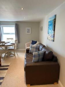 a living room with a brown leather couch and a table at St Margarets Penthouse Apartment in Ryde