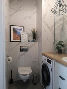 a white bathroom with a toilet and a sink at Apartamenty 48 Letnica in Gdańsk