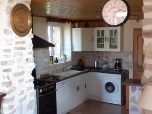eine Küche mit einem Waschbecken und einer Uhr an der Wand in der Unterkunft Gîte des Billaudes in Thuret
