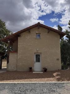 ein kleines Gebäude mit einer weißen Tür auf der Seite in der Unterkunft Gîte des Billaudes in Thuret