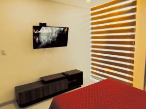 a bedroom with a bed and a tv on the wall at Private Garzonier Las Palmas in Santa Cruz de la Sierra