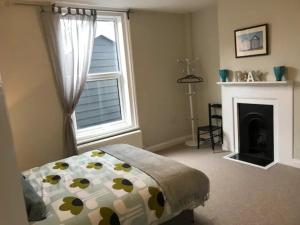 a bedroom with a bed and a fireplace and a window at St Margarets Modern Georgian 2 bedroom apartment in Ryde