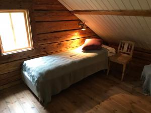 a bedroom with a bed and a chair in a cabin at Lilla Stubbetorp in Vimmerby