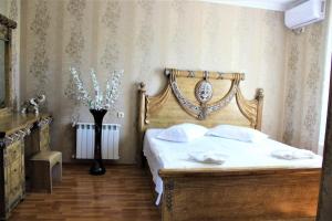 Schlafzimmer mit einem Bett mit einem Kopfteil aus Holz in der Unterkunft Hotel Oniks in Kutaissi