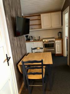 Skasenden的住宿－Finnskogen hyttegrend，厨房配有木桌,墙上配有电视。