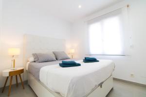 a bedroom with a white bed with two blue towels on it at Arenas house in Torrevieja +22 photos