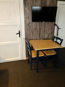mesa de madera con 2 sillas y TV en la pared en Finnskogen hyttegrend en Skasenden