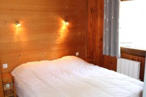 a bed in a room with a wooden wall at Chalet Les Bouleaux, la montagne des lamas in La Bresse