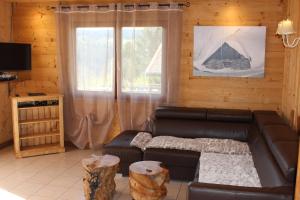 a living room with a leather couch and a window at Chalet Les Bouleaux, la montagne des lamas in La Bresse