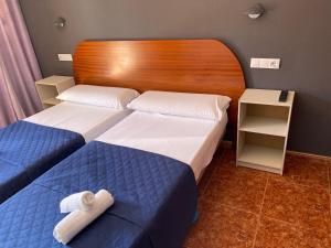 - 2 lits dans une chambre avec une tête de lit en bois dans l'établissement Hostal Tarik, à Tarifa