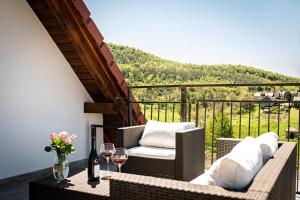 a balcony with wicker chairs and a table with wine glasses at Szigligeti Mandula Kert Vendégház in Szigliget