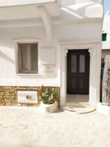 a white house with a black door and a potted plant at Narcissus Luxury Suites in Naxos Chora