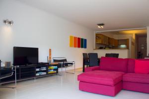a living room with a red couch and a tv at Ericeira (S. Lourenco) Apartment in Ribamar