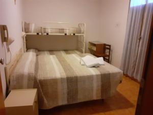 a small bedroom with a bed with a plaid blanket at HOTEL ROSSINI in Rimini