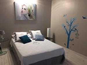 a bedroom with a bed with a painting on the wall at Les Chambres d'Hôtes d'Alice Dior in Blacé