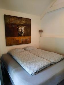 Luxe chalet Beekbergen nl في بيكبيرخين: غرفة نوم بسرير مع لوحة على الحائط