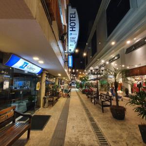 um centro comercial com bancos e pessoas a andar nele à noite em Hotel Gumz em Balneário Camboriú