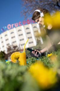 a woman sitting in the grass with a cell phone and a banana at Afyon Orucoglu Thermal Resort in Afyon