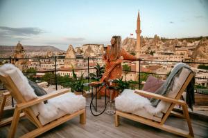 a woman standing on a balcony looking out over a city at Sato Cave Hotel in Goreme