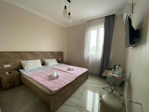 a bedroom with a bed with pink sheets and a tv at Family Hotel in Batumi