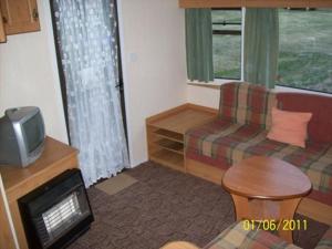 a living room with a couch and a tv at Domek Holenderski Jasieniec in Żabinki
