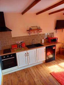 a kitchen with white cabinets and a black dishwasher at A New U Country Cottage Apartment 2 in Valentia Island