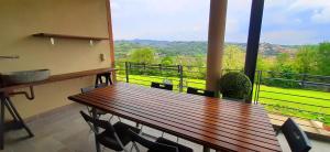 balkon z drewnianym stołem i krzesłami oraz widokiem na okolicę w obiekcie ConfinedeiSanti B&B w mieście Moriondo Torinese