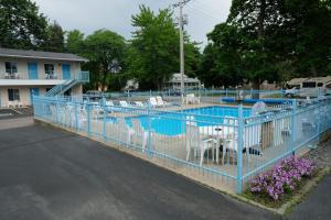 una valla azul alrededor de una piscina con sillas blancas en Starlite Motel en Wisconsin Dells