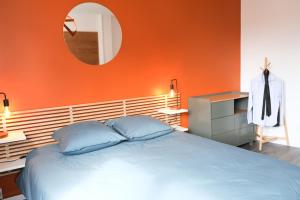 a bedroom with an orange wall with a bed and a mirror at Le Grand Chambord in Laval