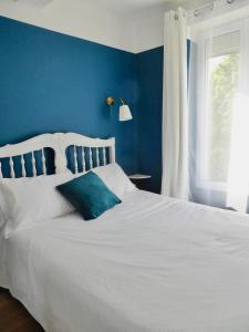 ein blaues Schlafzimmer mit einem weißen Bett und einer blauen Wand in der Unterkunft La Lavandière in Puimoisson