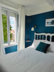 a blue bedroom with a white bed and a window at La Lavandière in Puimoisson
