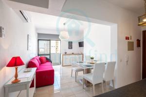een woonkamer met een roze bank en een tafel bij Apartment Algarve - Beach Front - Free Wifi - Air Con in Armação de Pêra