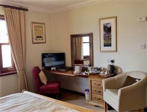 
a living room with a desk, chair and television at Ardno House B & B in Glencoe

