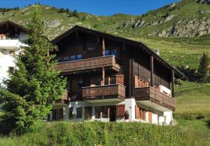 a large building with wooden balconies and a tree at Apartment Alouette Riederalp in Riederalp